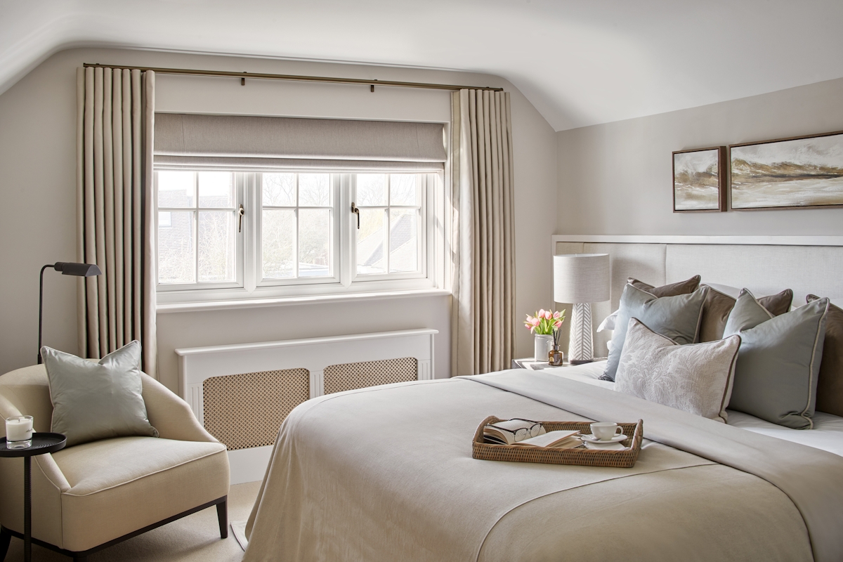 Bright, neutral beroom with Valentina linen cushion by LuxDeco and tray with coffee cup on the bed. Accent chair and Studio floor lamp by Visual Comfort & Co.