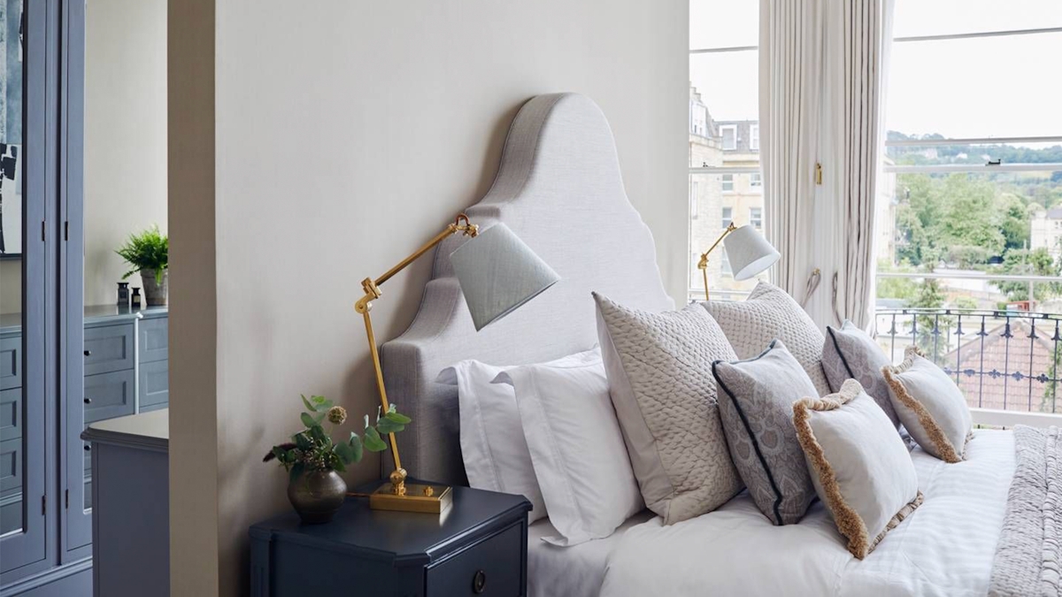 Simple and clean luxury bed frame with scatter cushion display and bedside tables with lamps