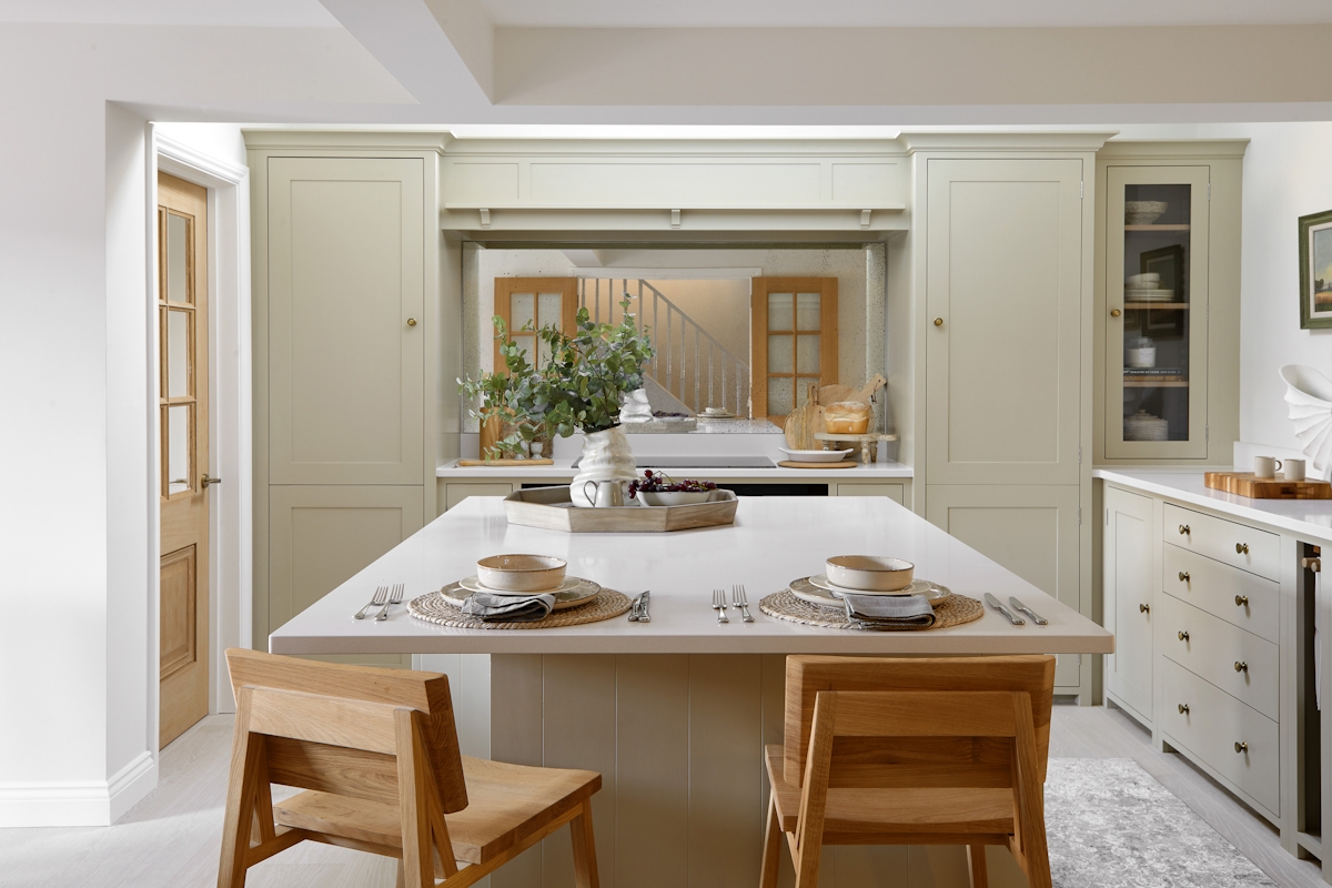 Calm white kitchen with bespoke cabinets, oak counter stools by Ethnicraft and inviting place setting on the island. Featuring the Parquet Tray and Melting Vase by LuxDeco
