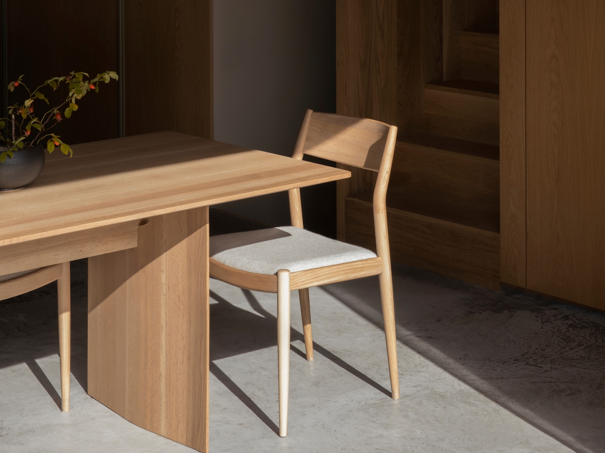 Norm Architects designed space with light wood dining table and chair on concrete floor